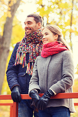 Image showing smiling couple hugging on bridge in autumn park