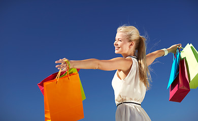 Image showing smiling woman with shopping bag rising hands