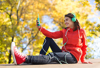 Image showing happy young woman with smartphone and headphones