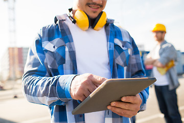 Image showing close up of builder with headphones and tablet pc