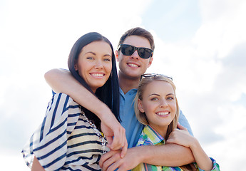 Image showing group of happy friends hugging over sky background