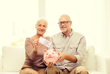 Image showing senior couple with money and piggy bank at home