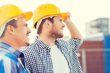 Image showing group of smiling builders in hardhats outdoors