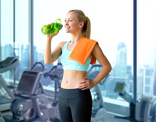 Image showing happy woman drinking water from bottle in gym