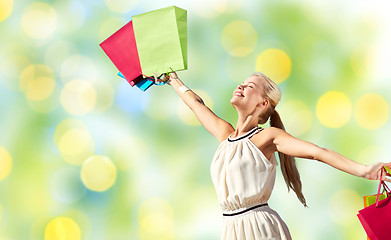 Image showing smiling woman with shopping bag rising hands