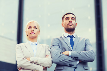 Image showing serious businessmen standing over office building