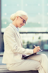 Image showing young smiling businesswoman with notepad outdoors