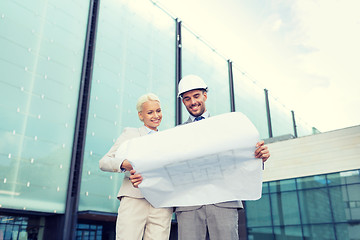 Image showing smiling businessmen with blueprint and helmets