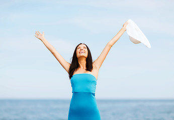 Image showing girl with hands up on the beach