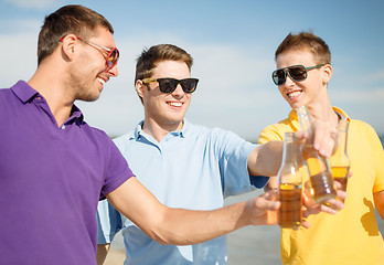 Image showing happy friends with beer bottles on beach