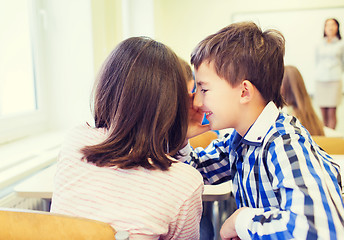 Image showing smiling schoolgirl whispering to classmate ear