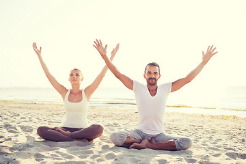 Image showing smiling couple making yoga exercises outdoors