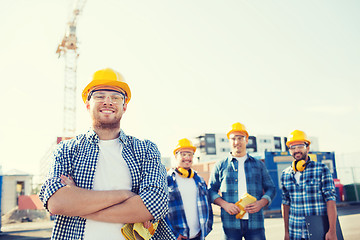 Image showing group of smiling builders in hardhats outdoors