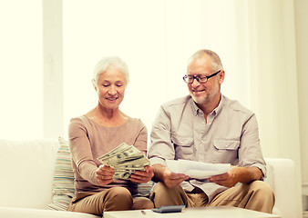 Image showing senior couple with money and calculator at home