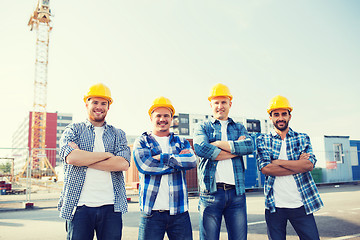 Image showing group of smiling builders in hardhats outdoors