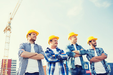 Image showing group of smiling builders in hardhats outdoors