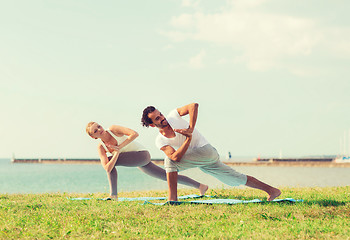 Image showing smiling couple making yoga exercises outdoors