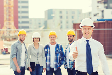 Image showing group of smiling builders in hardhats outdoors