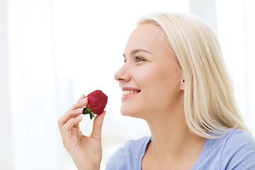 Image showing happy woman eating strawberry at home