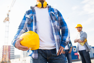 Image showing close up of builder holding hardhat at building