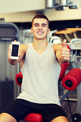 Image showing smiling young man with smartphone in gym