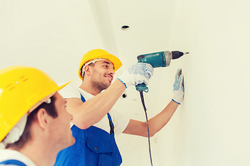 Image showing group of smiling builders with drill indoors