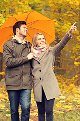 Image showing smiling couple with umbrella in autumn park