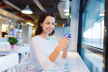 Image showing smiling woman with smartphone at cafe