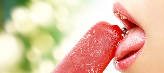 Image showing woman with pierced tongue licking fruit ice cream