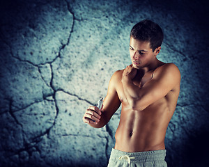 Image showing young male bodybuilder applying pain relief gel