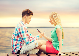 Image showing couple with smartphones sitting on bench