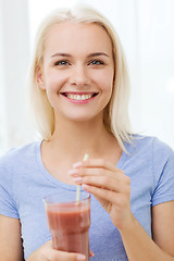 Image showing smiling woman drinking juice or shake at home