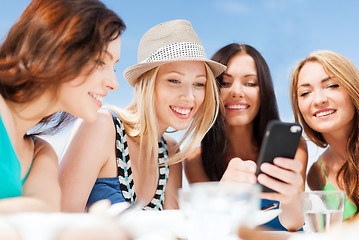 Image showing girls looking at smartphone in cafe on the beach