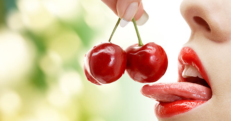 Image showing woman mouth with lips and tongue eating cherry