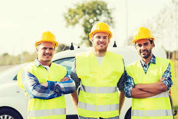 Image showing group of smiling builders in hardhats outdoors