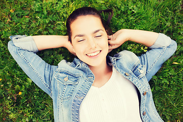 Image showing smiling young girl with closed eyes lying on grass