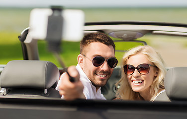 Image showing happy couple in car taking selfie with smartphone