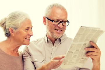 Image showing happy senior couple reading newspaper at home