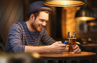 Image showing man with smartphone and beer texting at bar