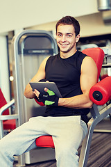 Image showing smiling young man with tablet pc computer in gym
