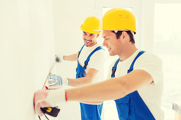 Image showing smiling builders with measuring tape indoors