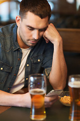 Image showing man with smartphone drinking beer at bar