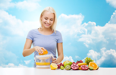 Image showing smiling woman squeezing fruit juice over sky