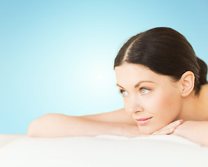 Image showing happy beautiful woman lying on massage desk at spa