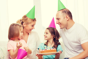 Image showing smiling family with two kids in hats with cake