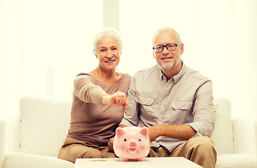 Image showing senior couple with money and piggy bank at home