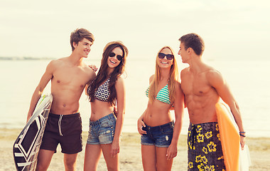 Image showing smiling friends in sunglasses with surfs on beach