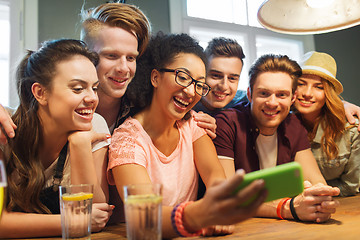 Image showing happy friends with smartphone taking selfie at bar