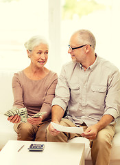 Image showing senior couple with money and calculator at home