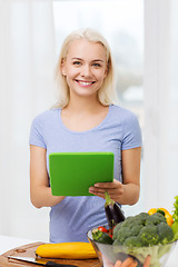 Image showing smiling young woman with tablet pc cooking at home